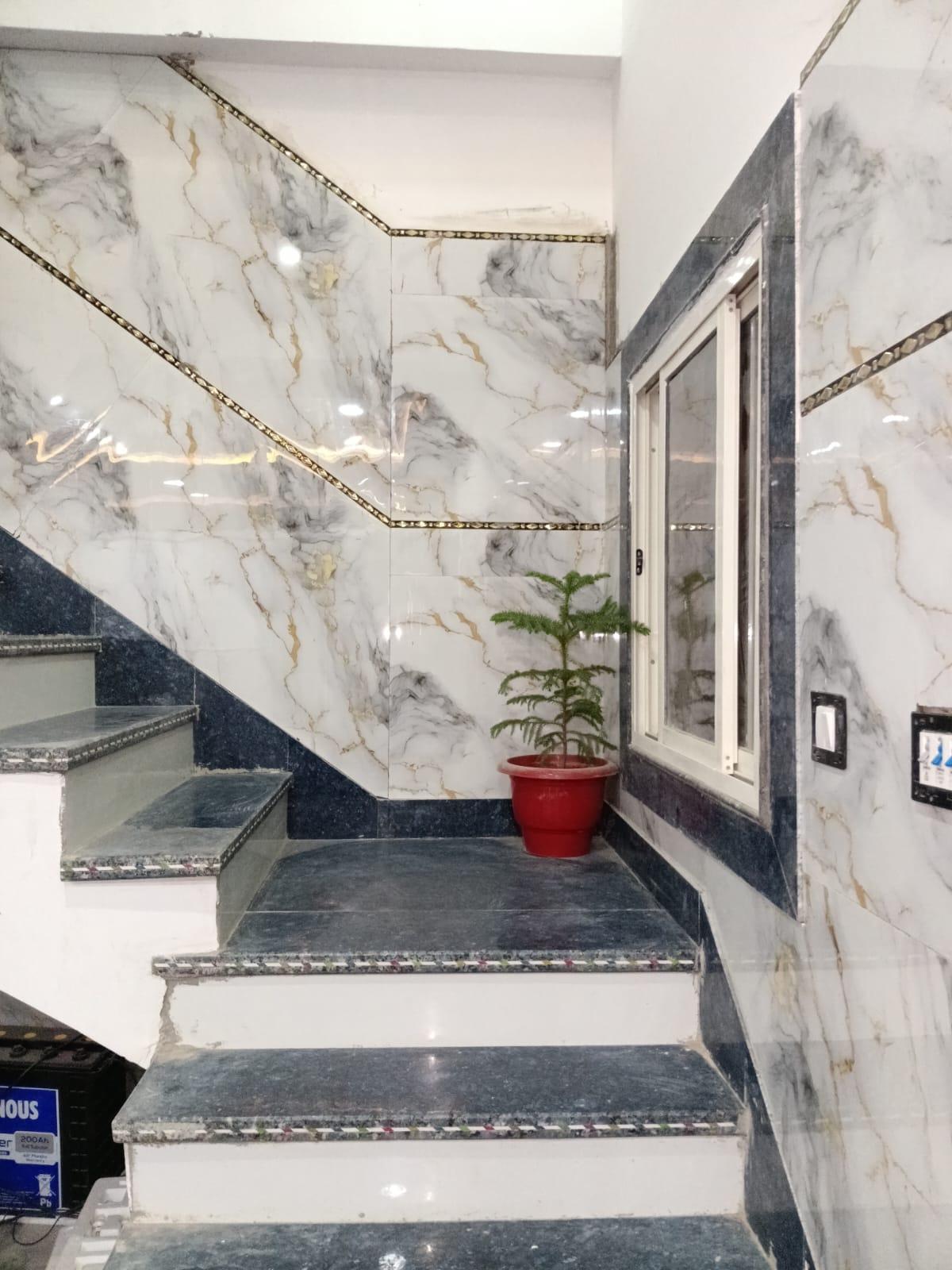 Staircase with marble-finish tiled walls and a potted plant