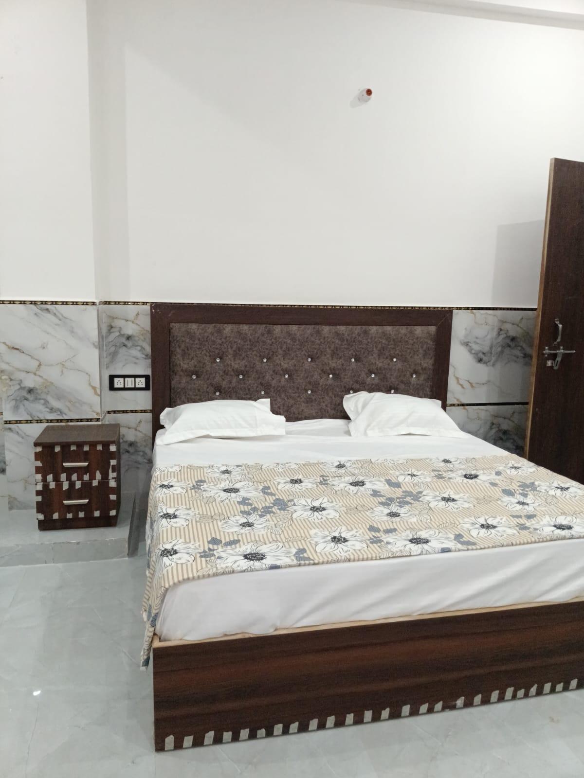 Double bed with upholstered headboard, floral bedspread and wooden bedside table